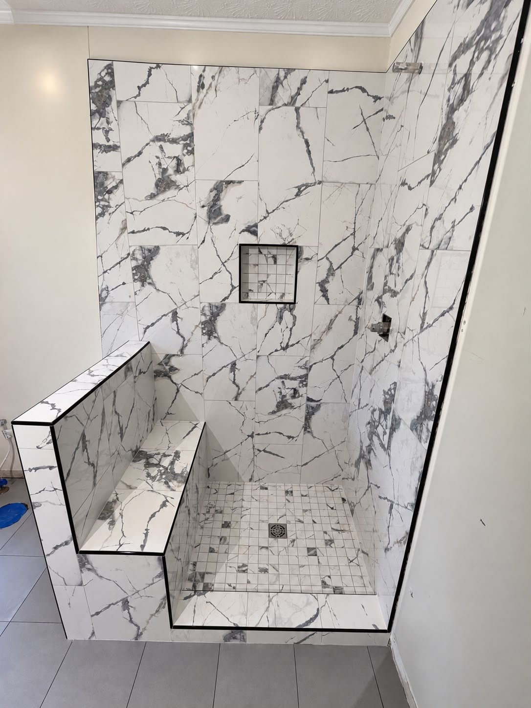 Completed custom shower with a mobility-friendly built-in bench and marble-look tile