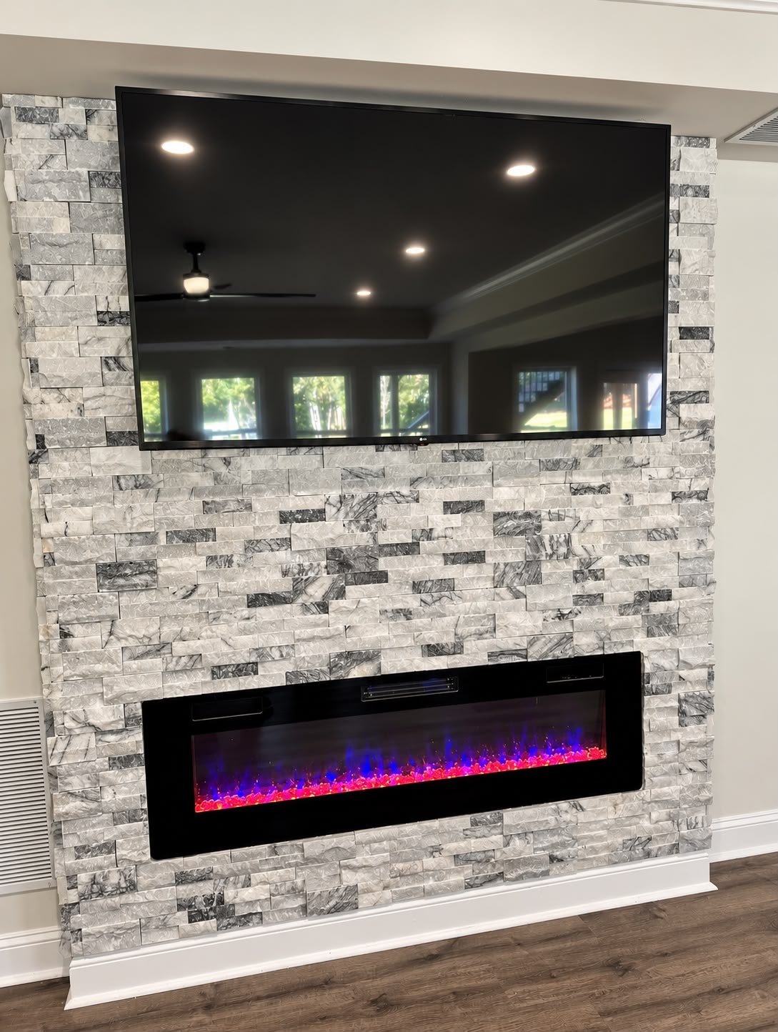 Completed basement fireplace feature wall with stone finish and mounted television