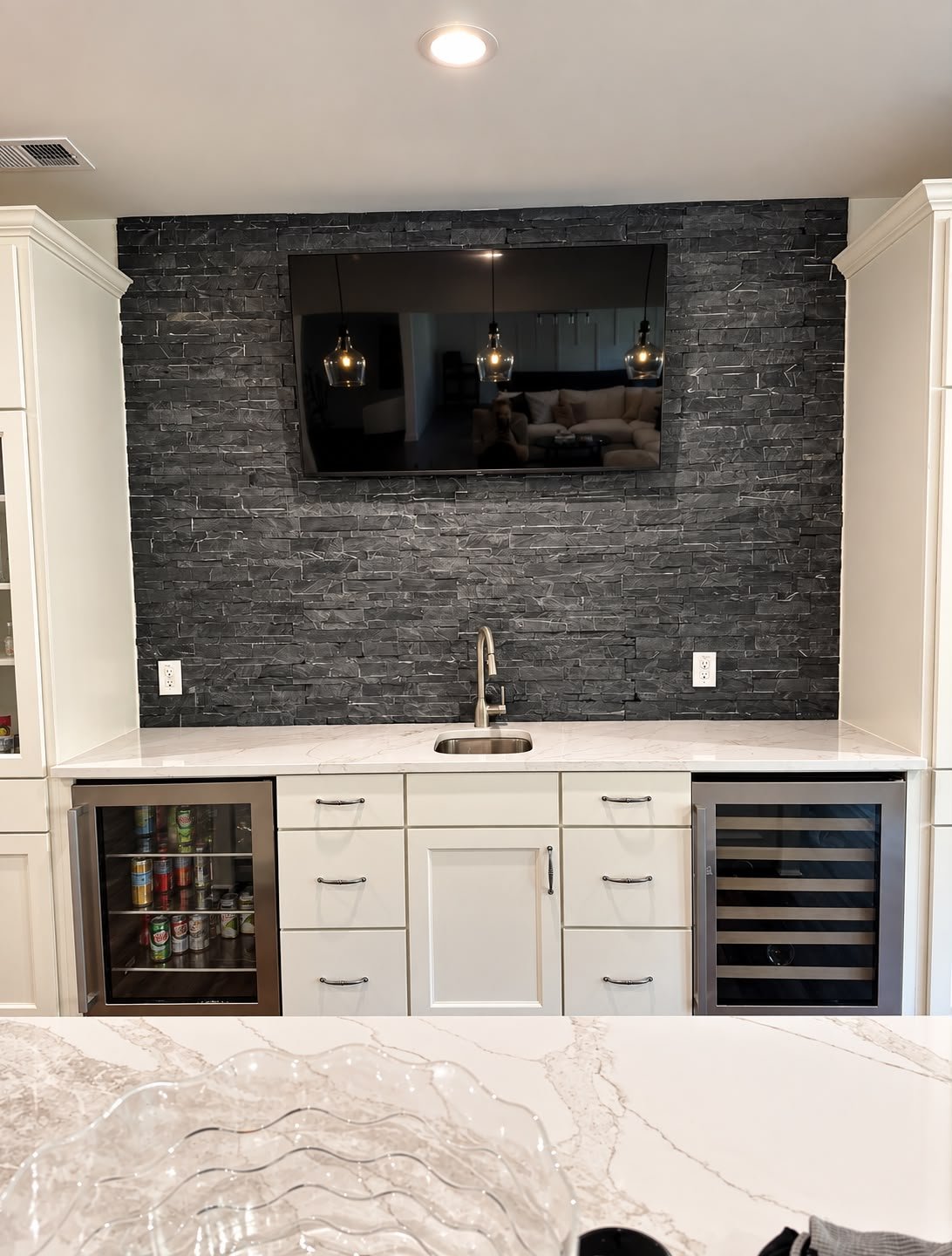 Detailed view of the finished wet bar cabinetry, counter and stone wall