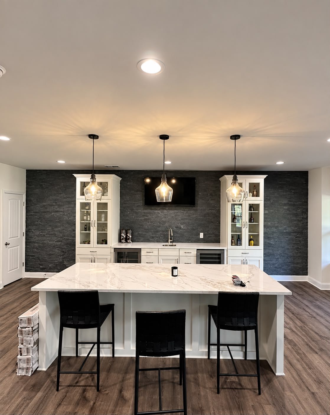 Completed basement wet bar with stone feature wall and large island