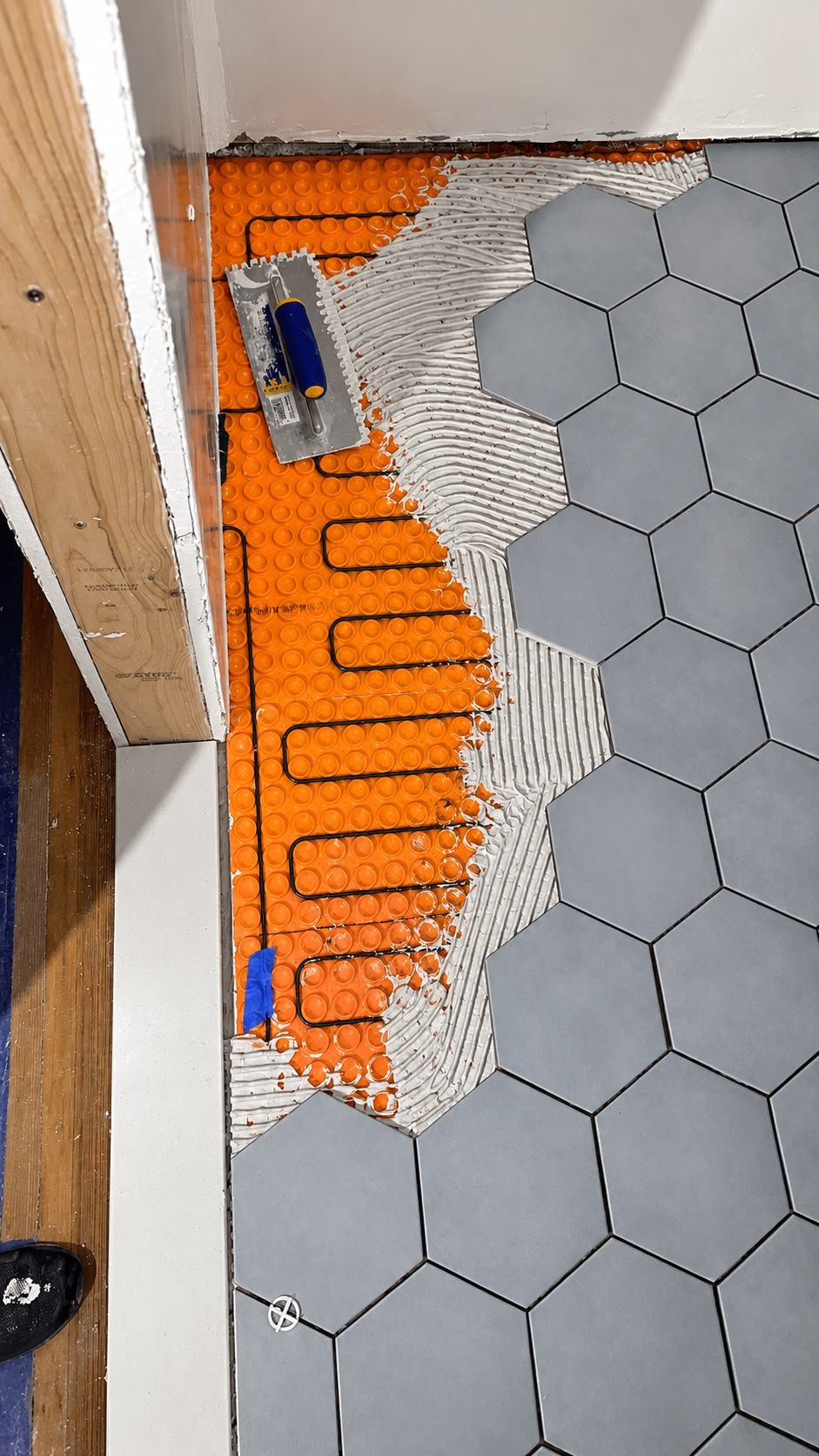 Radiant floor heating system being installed beneath gray hexagonal tile
